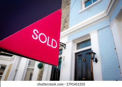 Estate agent SOLD sign with houses in background