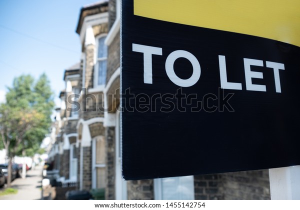 Estate agent \'TO LET\' sign on street of typical\
British street