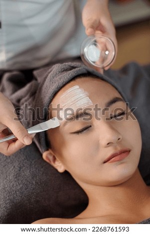 Esthetician applying moisturizing mask on face of young woman ストックフォト © 