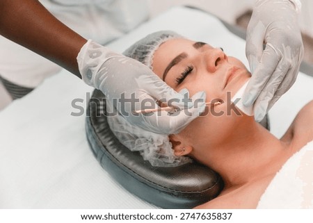 Esthetician hands using tool extractor to clean woman's facial pores during skincare treatment