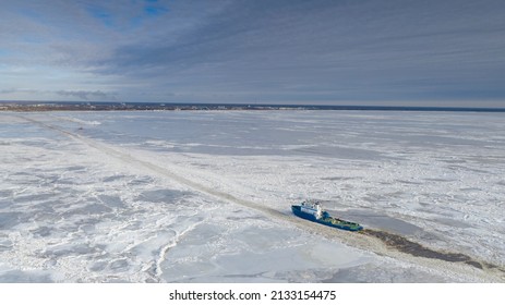 Pärnu, Estonia - 27.02.2022: Aerial View To The Ice Breaker Assisting Cargo Ship To Reach The Harbor Via Waterway Through  The Frozen Sea Bay