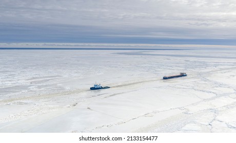 Pärnu, Estonia - 27.02.2022: Aerial View To The Ice Breaker Assisting Cargo Ship To Reach The Harbor Via Waterway Through  The Frozen Sea Bay