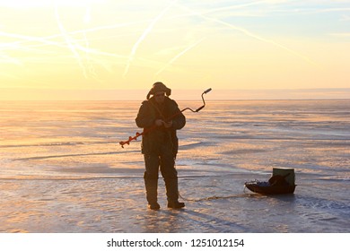 Pärnu, Estonia February 17 2017: Lonely Ice Fishing Anglers On Ice In Pärnu Bay, Baltic Sea, Estonia And Yellow Sunrise