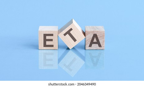 ETA word written on wood block. ETA word is made of wooden building blocks lying on the blue table, business concept. ETA short for ESTIMATED TIME OF ARRIVAL