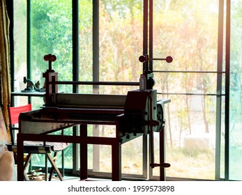 Etching Press, Art Equipment For Printmaking. Old Red Etching Press In Art Studio Near Glass Sliding Door On The Green Garden Background Outside The Building.