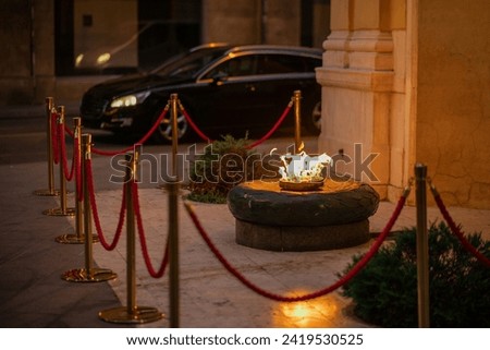 Eternal flame at a small chaplet in the city of Sarajevo at an evening. Flame surrounded by protective fence, lush and fierce flame.
