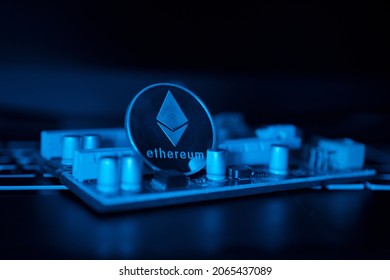 ETH.  Cryptocurrency. SIlver coin with Ethereum sign on pci riser for mininig. Blue light