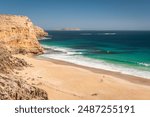 Ethel Wreck Beach with people walking along viewed from the lookout with surfers can be seen in the ocean on a bright day