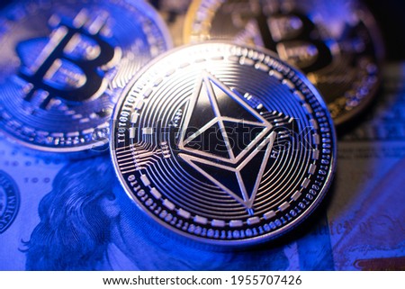 Ethereum on one hundred dollar banknote. Silver coin with Ethereum icon. Digital crypto currency technology. Bitcoins in the background in silver and gold