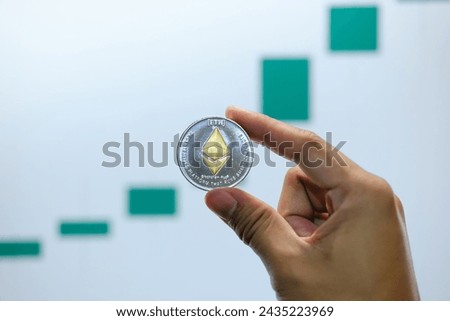 Ethereum physical coin symbol on a laptop with uptrend price graph background, future concept financial currency, cryptocurrency sign.