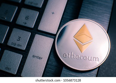 Ethereum. Silver Ethereum coin with gold Ethereum symbol on  a laptop keyboard next to the Enter key