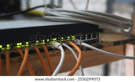 Ethernet cables connected to a network switch with blinking green lights showing data transfer and network activity on a wooden surface