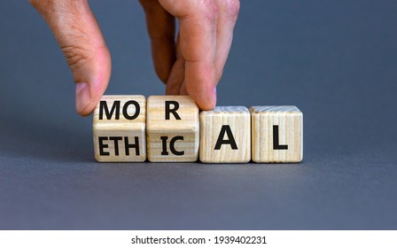 Ethical or moral symbol. Businessman turns wooden cubes and changes the word 'moral' to 'ethical' on a beautiful grey table, grey background. Business and ethical or moral concept. Copy space.