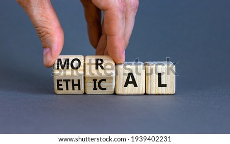 Ethical or moral symbol. Businessman turns wooden cubes and changes the word 'moral' to 'ethical' on a beautiful grey table, grey background. Business and ethical or moral concept. Copy space.