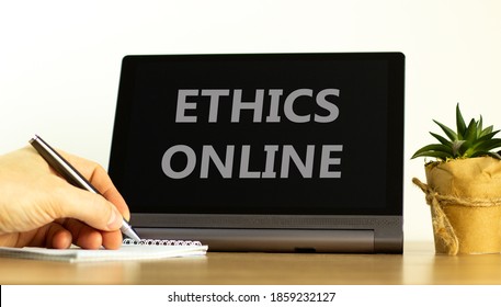 Ethics online. Tablet with words ethics online. Male hand with pen, house plant. Copy space. Business and ethics online concept.