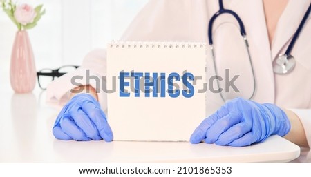 ethics, text on white notepad paper in hands doctor. notepad near capsules and pills. blue stethoscope, medicine concept.