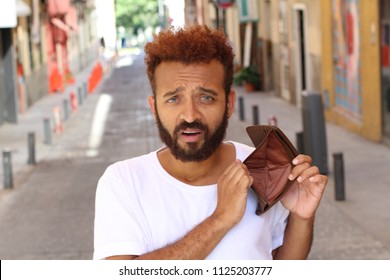 Ethnic broke guy with empty wallet outdoors 