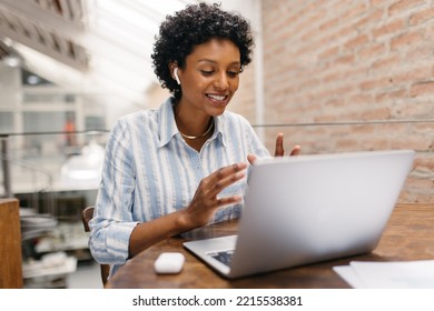 Ethnic Small Business Owner Having An Online Meeting In A Warehouse. Female Entrepreneur Video Calling Her Business Partners On A Laptop. Happy Businesswoman Running An Online Startup.