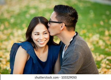 Ethnic Young Couple Sitting In A Pile Of Leaves