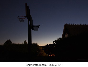 Ethnographic house with basketball court with two baskets at Saaremaa island, Estonia. Outdoor basketball hoop dark silhouette. Night shot. 