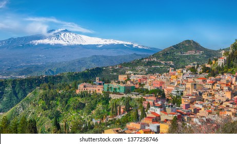 Etna volcano and Taormina town aerial panoramic view. Roofs of a lot of buldings. Smoking snow-capped Mount Etna volcano. Taormina, Sicily, Italy.