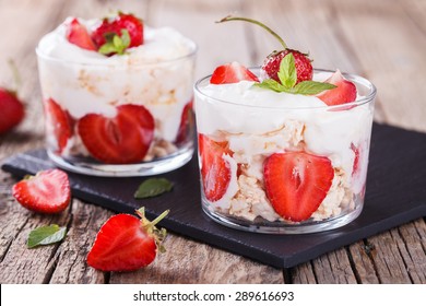 Eton Mess - Strawberries with whipped cream and meringue in a glass beaker. Classic British summer dessert.selective focus - Shutterstock ID 289616693