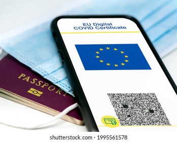 EU Digital COVID Certificate with the QR code on the screen of a mobile phone over a surgical mask and a passport. Immunity from Covid-19. Travel without restrictions.