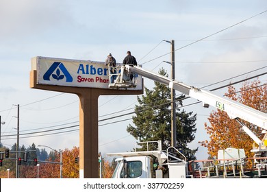 EUGENE, OR - NOVEMBER 4, 2015: Two workers installing a new sign at an Albertsons location at Oakway Center.
