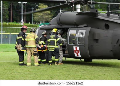 Eugene, Oregon, USA Â?Â? May 2, 2012: In Eugene, OR Local Emergency Services And National Guard Work Together In A Disaster Response Drill. Unidentified Firemen Carry An Injured Person To The Helicopter.