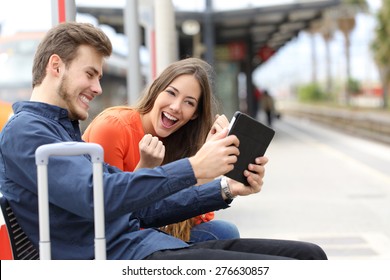 Euphoric Couple Watching Movies Or Playing Games In A Tablet In A Train Station