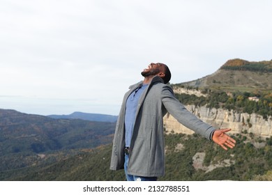 Euphoric Man With Black Skin Outstretching Arms Celebrating In Winter In The Mountain