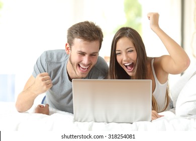 Euphoric marriage winning using a laptop lying on a bed at home - Powered by Shutterstock