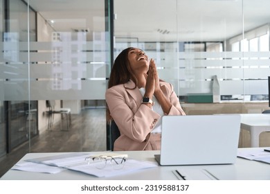 Euphoric professional young African American business woman executive feeling happy about financial work results, corporate goals achievement getting new job offer sitting with laptop in office. - Shutterstock ID 2319588137