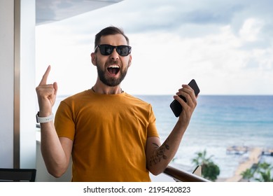 Euphoric soccer fan is watching soccer play live broadcast online on his mobile phone, betting on his favourite team and celebrating money win. - Shutterstock ID 2195420823