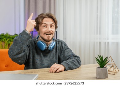 Eureka. Thoughtful clever inspired Caucasian man make gesture raises finger came up with creative plan feels excited with good idea inspiration motivation question at home apartment. Guy sits at desk