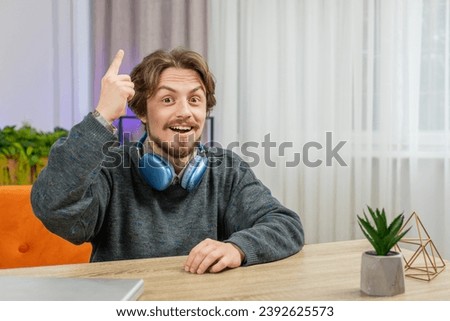 Eureka. Thoughtful clever inspired Caucasian man make gesture raises finger came up with creative plan feels excited with good idea inspiration motivation question at home apartment. Guy sits at desk