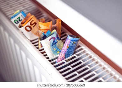 euro banknotes in a central heating radiator, the concept of expensive heating costs, close-up - Shutterstock ID 2075050663
