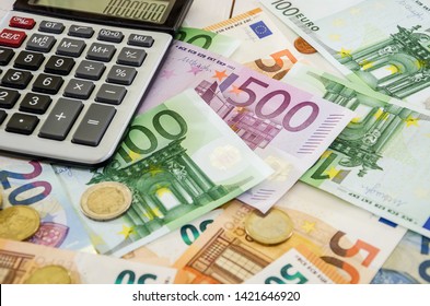 euro banknotes, coins and calculator on white table - Shutterstock ID 1421646920