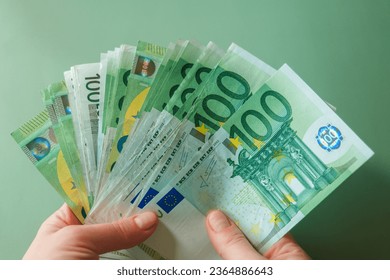 euro banknotes in female hands on a green background.salary of a woman in the Eurozone. Income of women in European countries.Hands holding euro money.Earnings and spending in the Eurozone - Shutterstock ID 2364886643