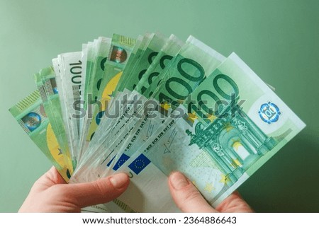 euro banknotes in female hands on a green background.salary of a woman in the Eurozone. Income of women in European countries.Hands holding euro money.Earnings and spending in the Eurozone