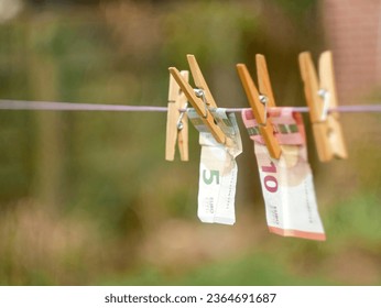 Euro Banknotes hanging from a clothesline, with clothespins, on blurry background. For tainted money concept or money laundering. - Shutterstock ID 2364691687