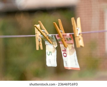 Euro Banknotes hanging from a clothesline, with clothespins, on blurry background. For tainted money concept or money laundering. - Shutterstock ID 2364691693