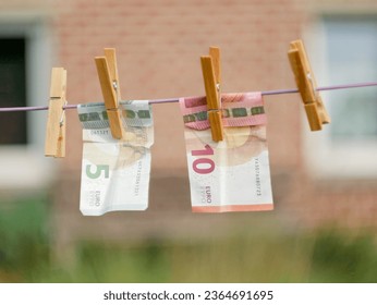 Euro Banknotes hanging from a clothesline, with clothespins, on blurry background. For tainted money concept or money laundering. - Shutterstock ID 2364691695