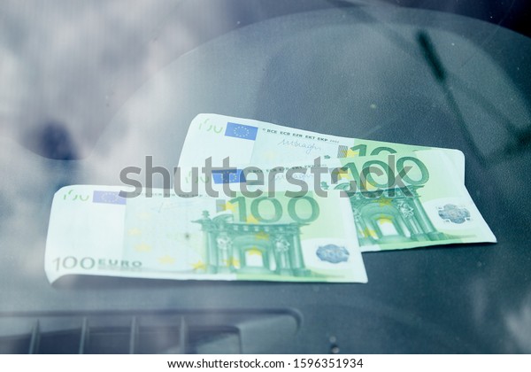 Euro banknotes on the black\
dashboard and their reflection in the windshield inside of a\
car
