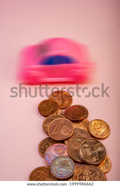 Euro cent coins\
and a blurred toy car lie on a pink background. Business concept.\
Cover. Background for design.\
