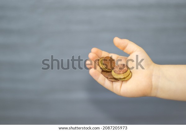 euro cents in kids hand. boy in black t\
shirt is counting or holding old, wiped coins. money savings,\
business. one, two, ten and fifty euro cents. Learning financial\
literacy, responsibility