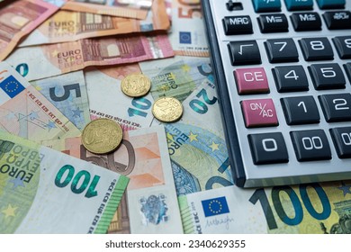 Euro coin and calculator above euro bills. Saving and finance concept. Investment theme