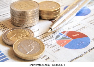 Euro money coins and ball pen on a global income report with charts