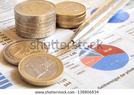 Euro money coins and ball pen on a global income report with charts