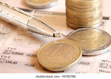 Euro money coins and silver colored ball pen on top of stock market chart